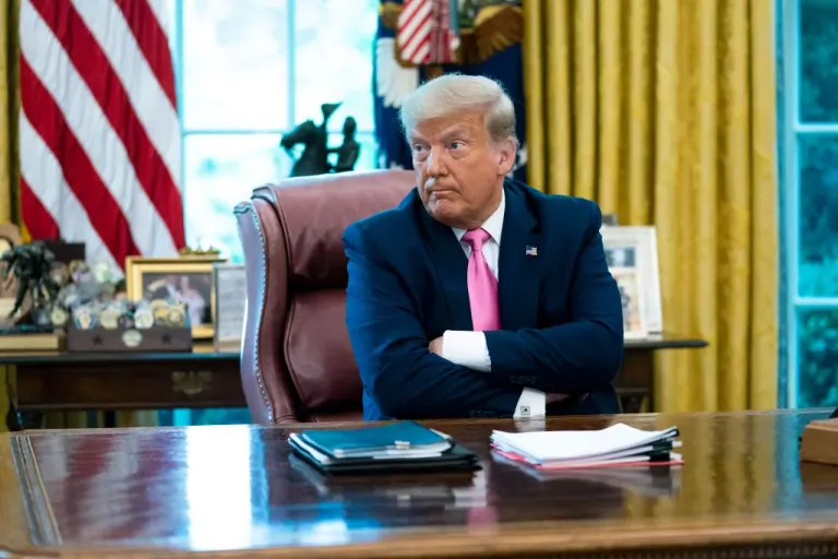 President Donald Trump sits behind a desk in the Oval Office.
