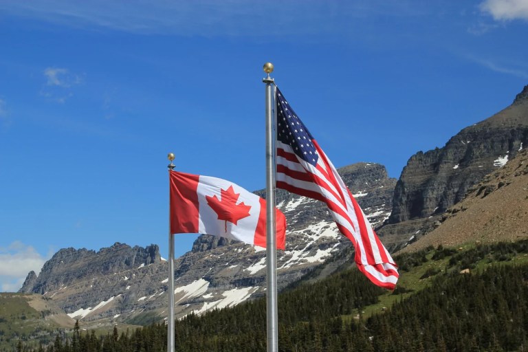Canadian and American flags ripple in the wind.