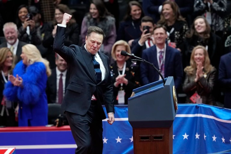 Elon Musk pretends to plant the American flag on Mars as he speaks at an indoor inauguration parade event in Washington, Monday, Jan. 20, 2025.