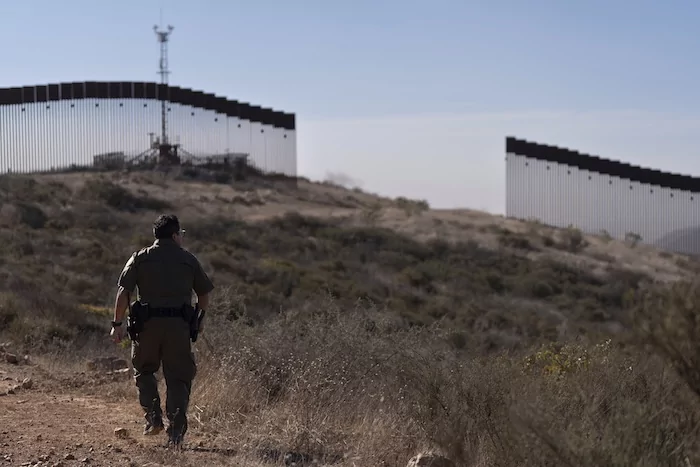 A Border Patrol agent walks toward a gap in one of two border walls separating Mexico from the United States, Thursday, Jan. 23, 2025, in San Diego.