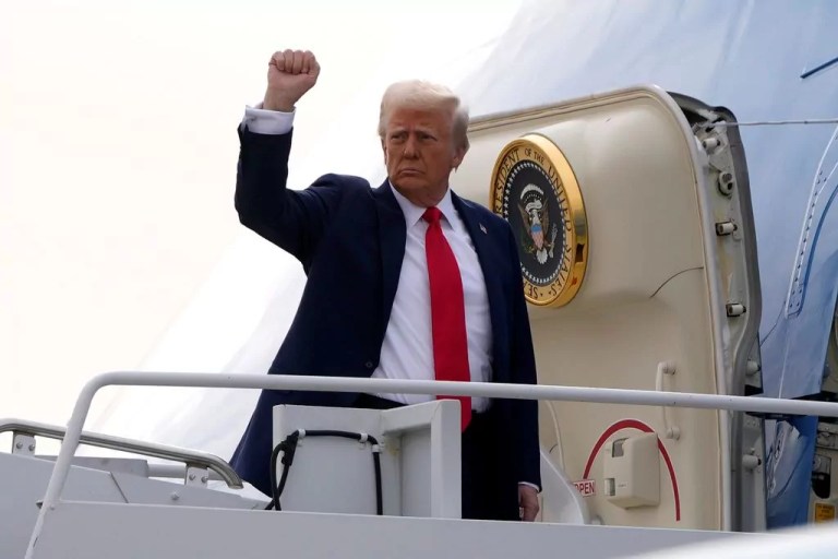 President Donald Trump raises his fist as he boards Air Force One, Jan. 25, 2025.