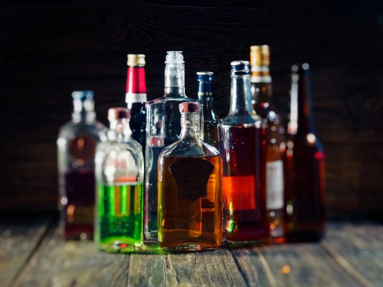 A group of various bottles of alcohol on a wooden bar counter.