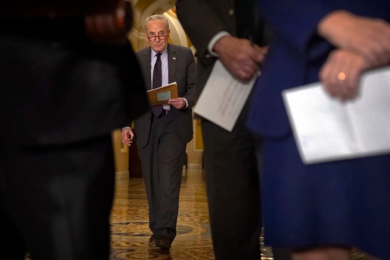 Senate Minority Leader Chuck Schumer (D-NY) stands as fellow senators speak to reporters on Tuesday, Jan. 14, 2025, on Capitol Hill in Washington.