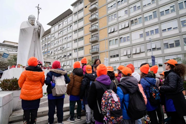 A group of children from a primary school pray for Pope Francis in front of the statue Pope John Paul II outside Agostino Gemelli Polyclinic in Rome, Wednesday, Feb. 19, 2025, where the Pontiff is hospitalized since Friday, Feb. 14.
