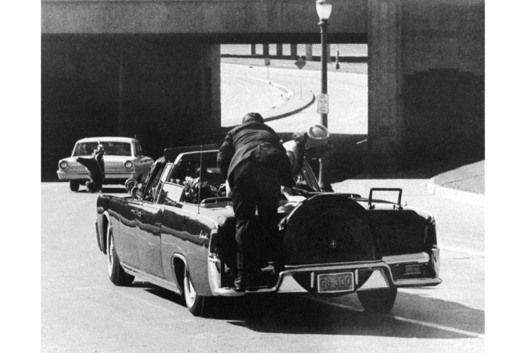 FILE - In this Friday, Nov. 22, 1963 file photo, President John F. Kennedy slumps down in the back seat of the Presidential limousine as it speeds along Elm Street toward the Stemmons Freeway overpass in Dallas after being fatally shot. First lady Jacqueline Kennedy leans over the president as Secret Service agent Clint Hill pushes her back to her seat. (AP Photo/James W. 