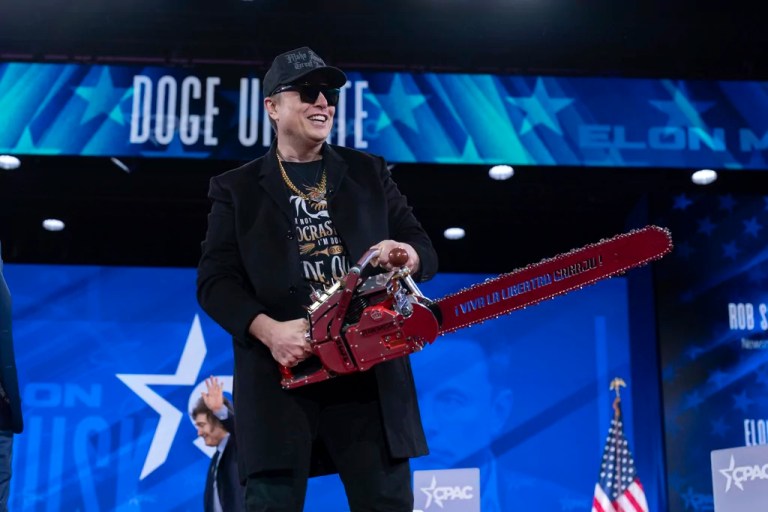 Elon Musk hold a chainsaw as he arrives to speak at the Conservative Political Action Conference, CPAC, at the Gaylord National Resort