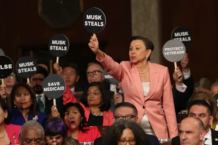 Rep. Nydia Velazquez, D-N.Y., holds a protest sign with fellow Democrats as President Donald Trump addresses a joint session of Congress at the Capitol in Washington, Tuesday, March 4, 2025.