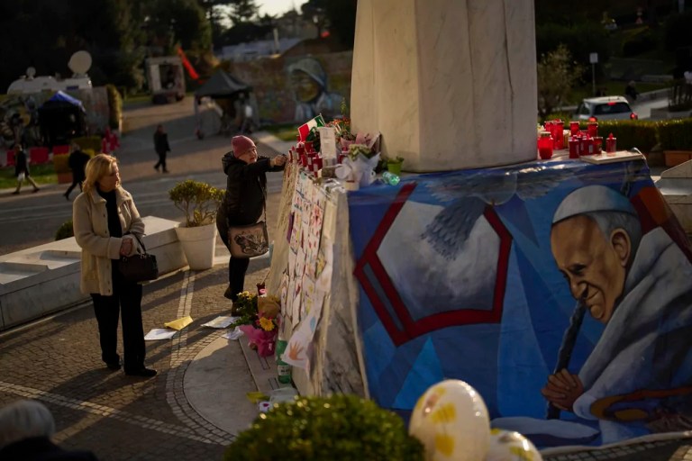 A woman places a Christian rosary at the statue of Pope John Paul II outside the Agostino Gemelli hospital in Rome, Thursday, March 6, 2025.