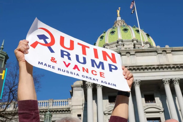 An anti-Trump protester holds a placard outside of the Pennsylvania State Capitol. (Photo by Paul Weaver / SOPA Images / LightRocket via Getty Images)