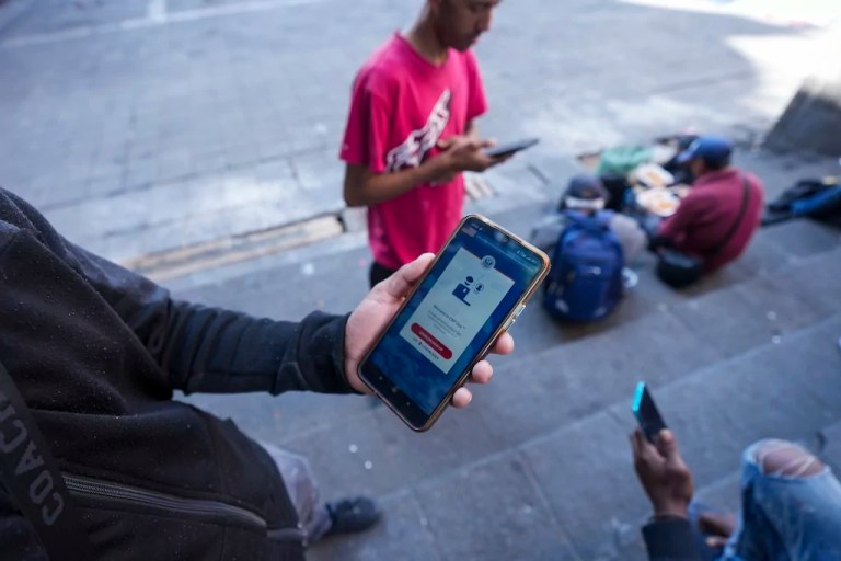 Venezuelan migrant Yender Romero shows the Customs and Border Protection One app on his cell phone, which he said he used to apply for asylum in the United States and is waiting on an answer, at a migrant tent camp outside La Soledad church in Mexico City, Monday, Jan. 20, 2025, the inauguration day of President Donald Trump.