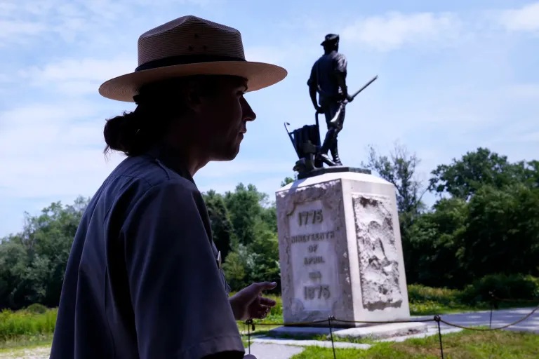 Minute Man park ranger and historic weapons specialist Jarrad Fuoss walks past the approximate area where five Revolutionary War musket balls were found, which are believed to have been fired at the British by colonial militia men, at Minute Man National Historical Park, Monday, July 15, 2024, in Concord, Massachusetts. Archeologists say the musket balls date back nearly 250 years and were fired during one of the first battles in the Revolutionary War. At left is park museum curator Nicole Walsh.