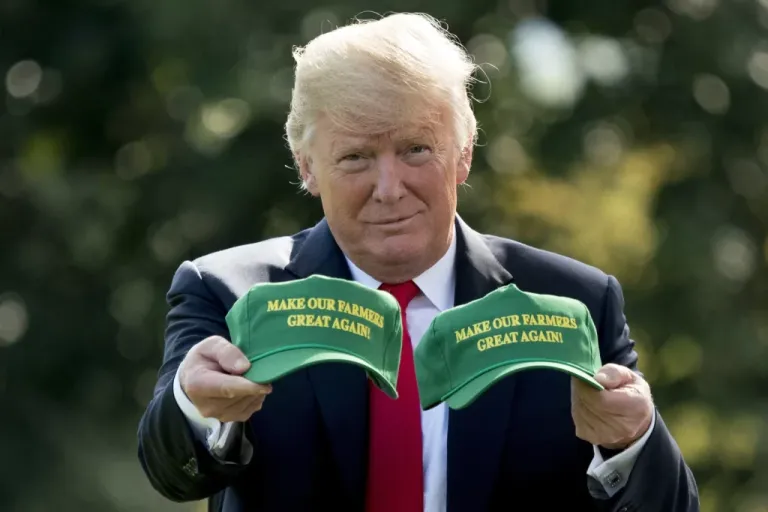 President Donald Trump holds up hats that read 