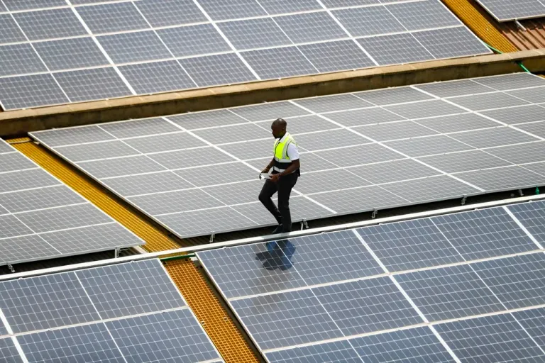 Mark Munyua, CP solar's technician, examines solar panels on a roof.