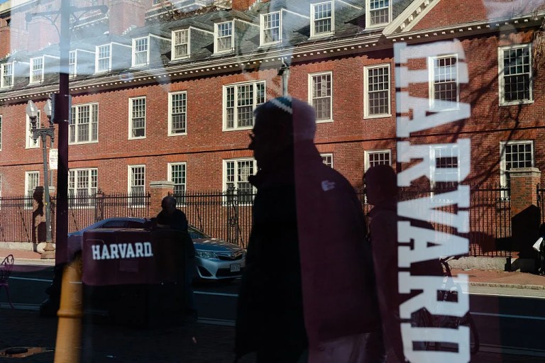 Harvard University is reflected in the window of a merchandise store across the street from the school, April 17, 2025, in Cambridge, Massachusetts.