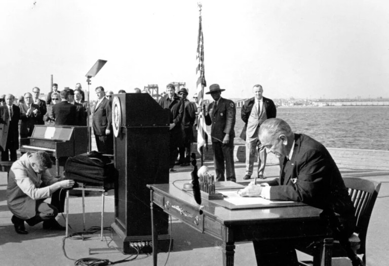 In this Oct. 3, 1965, file photo, President Lyndon B. Johnson sits at his desk on Liberty Island in New York Harbor as he signs a new immigration bill. It was presented as a symbolic move. Fifty years later, there's little that hasn't been changed as a result of the Hart-Celler Act. A country that was almost entirely native-born in 1965 now has a significant foreign-born population; demographic diversity has spread to every region, expanding a black-and-white racial paradigm into a multi-colored one. Americans have gleefully adopted musical genres and foods that have immigrant origins while remaining conflicted and uneasy politically over who's here, legally and not.