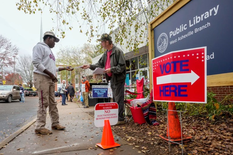 Stephen McCutcheon, right, gives a sample Republican ballot to Douglas Frick outside the West Asheville Public Library on Election Day, Tuesday, Nov. 5, 2024 in Asheville, North Carolina.