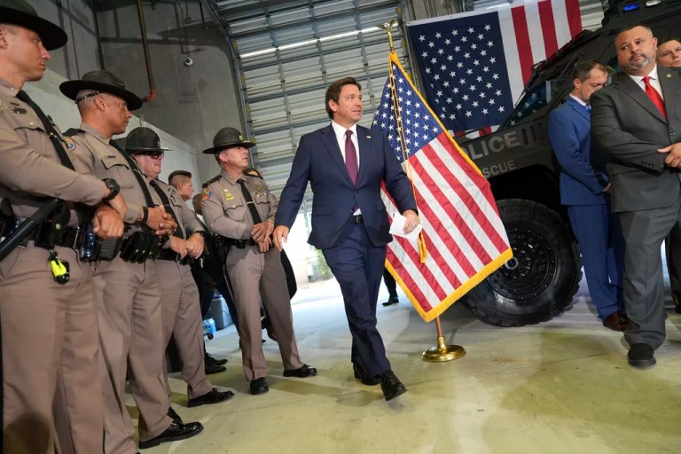 Officers of the Florida Highway Patrol, left, look on as Gov. Ron DeSantis (R-FL) arrives for a press conference about a recent immigration enforcement operation, at the South Florida office of U.S. Immigration and Customs Enforcement and Enforcement and Removal Operations, Thursday, May 1, 2025, in Miramar.