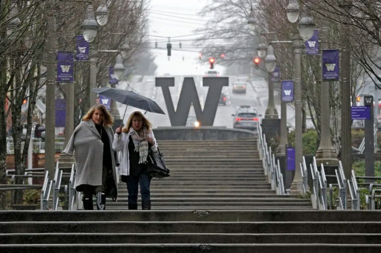 Two pedestrians share an umbrella in the rain, Friday, Dec. 29, 2017, in downtown Tacoma, Washington.