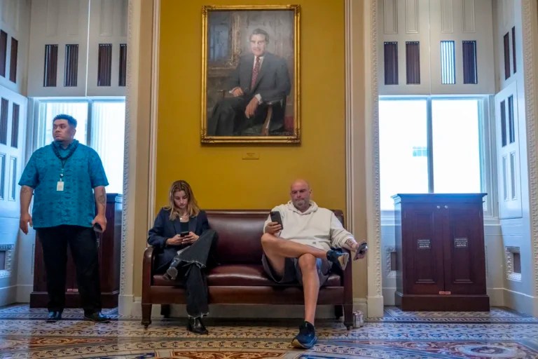 Sen. John Fetterman (D-PA) sits under a portrait near the Senate chamber of former Senate Majority Leader Bob Dole, as the Senate works to avert a partial government shutdown ahead of the midnight deadline, at the Capitol in Washington, Friday, March 14, 2025.