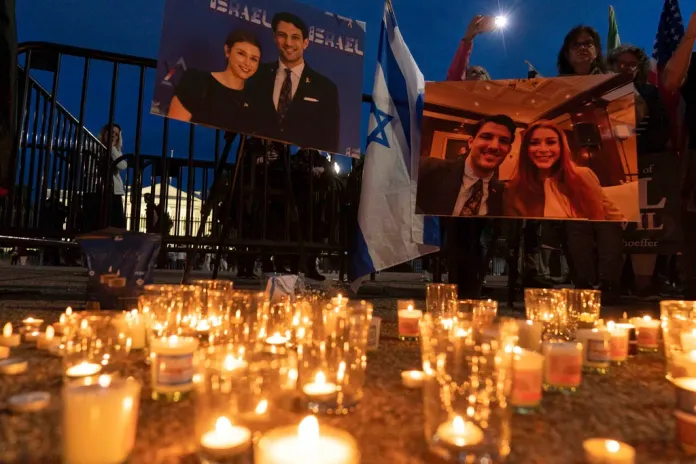 People gather to light candles in a makeshift memorial to honor Yaron Lischinsky and Sarah Milgrim.