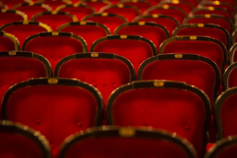 Numbered theater chairs upholstered in burgundy.