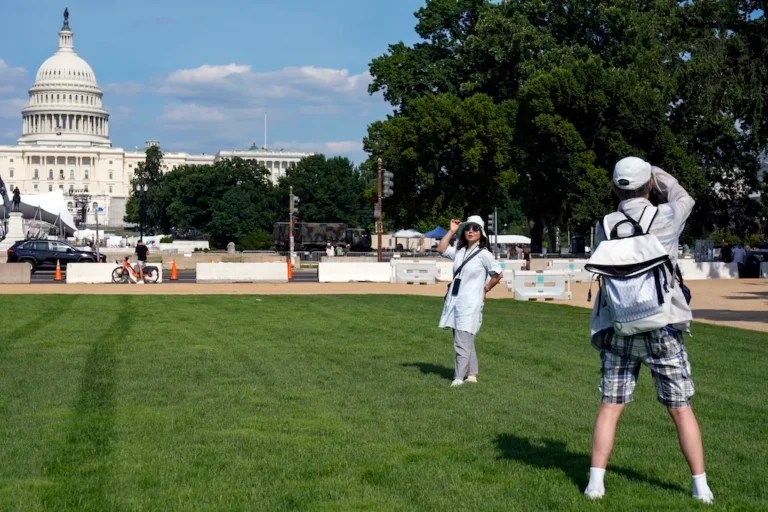 A visitor poses for a photo on the National Mall near the U.S. Capitol, Wednesday, July 3, 2024, in Washington, ahead of the Fourth of July celebrations. (AP Photo/Mariam Zuhaib)