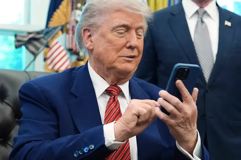 President Donald Trump silences his mobile phone which rang two times as he was speaking to reporters after signing executive orders regarding nuclear energy.