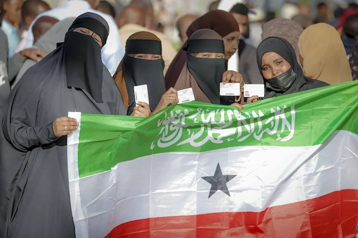 People display the Somaliland flag as they wait to cast their vote in 2024.