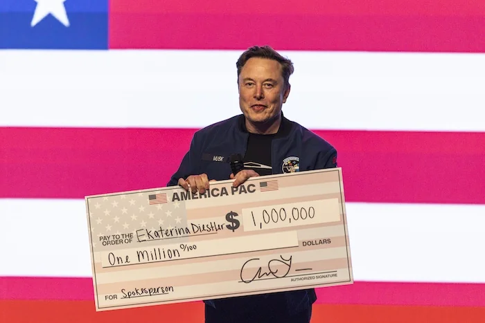 Elon Musk holds up a check during a town hall Sunday, March 30, 2025, in Green Bay, Wisconsin.