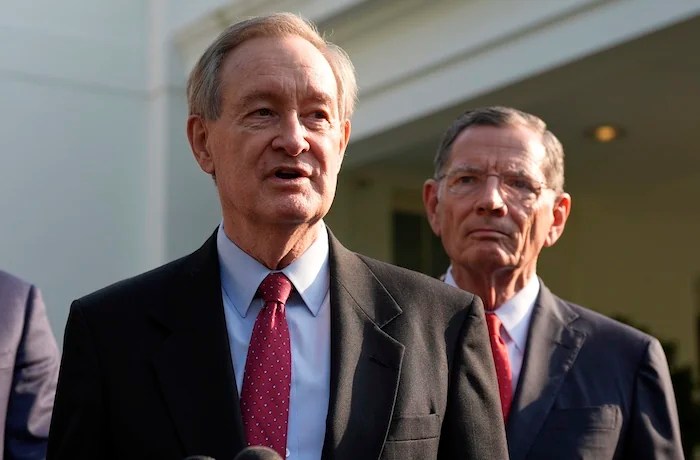 Sen. John Barrasso, R-Wyo., listens as Sen. Mike Crapo, R-Idaho, speaks with reporters after meeting with President Donald Trump