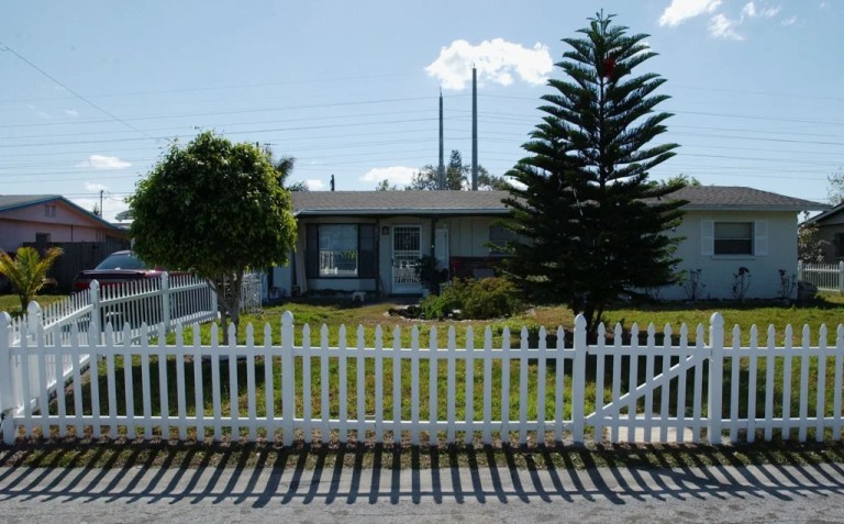 A white picket fence surrounds a house.