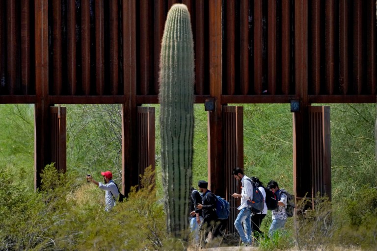 A group claiming to be from India walk past open border wall storm gates after crossing through the border fence in the Tucson Sector of the U.S.-Mexico border, Aug. 29, 2023, in Organ Pipe Cactus National Monument near Lukeville, Arizona.