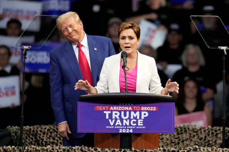Republican presidential nominee former President Donald Trump listens as Arizona Senate candidate Kari Lake speaks at a campaign rally at the Findlay Toyota Arena Sunday, Oct. 13, 2024, in Prescott Valley, Ariz.