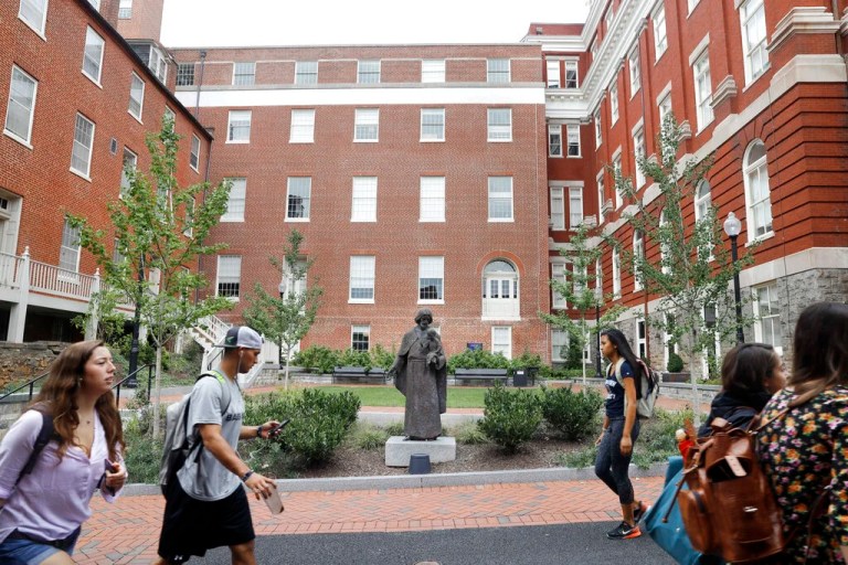 Students walk past a Jesuit statue in front of Freedom Hall, center, formerly named Mulledy Hall, on the Georgetown University campus, Thursday, Sept. 1, 2016, in Washington.