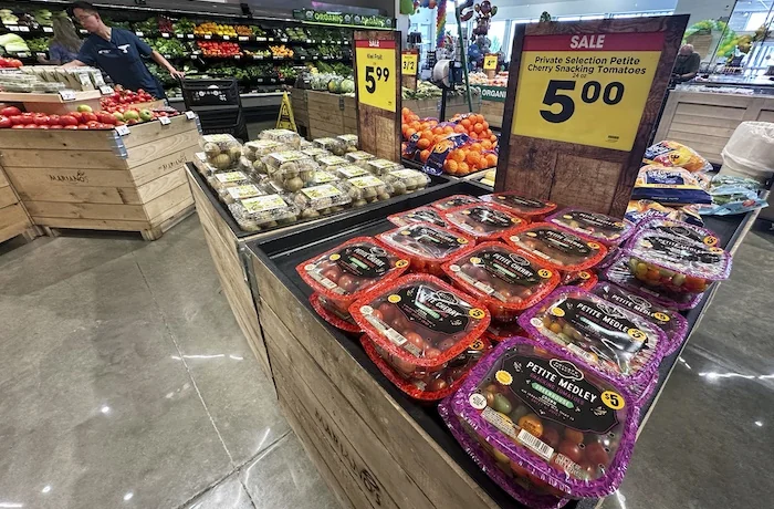 Tomatoes are displayed as a customer shops at a grocery store in Glenview, Ill., Tuesday, July 15, 2025.