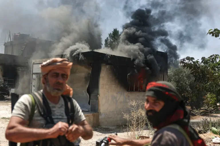 Bedouin fighters stand in front a burned shop at Mazraa village on the outskirts of Sweida city, during clashes between the Bedouin clans and Druze militias, southern Syria, Friday, July 18, 2025.