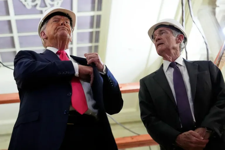 President Donald Trump, left, reaches for a document of cost figures as Federal Reserve Chairman Jerome Powell watches during a visit to the Federal Reserve, Thursday, July 24, 2025, in Washington.