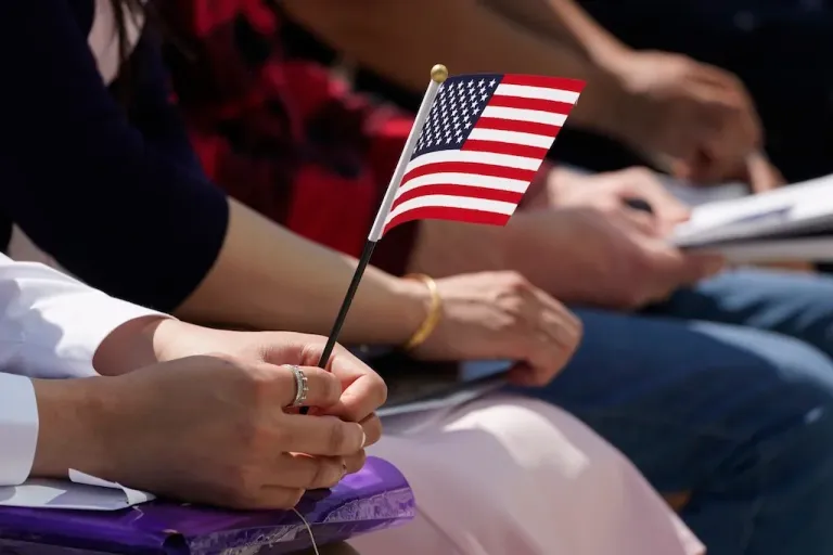 FILE - A new citizen holds the American flag during a Naturalization Ceremony at Indianapolis Motor Speedway, May 17, 2022, in Indianapolis. (AP Photo/Darron Cummings, File)
