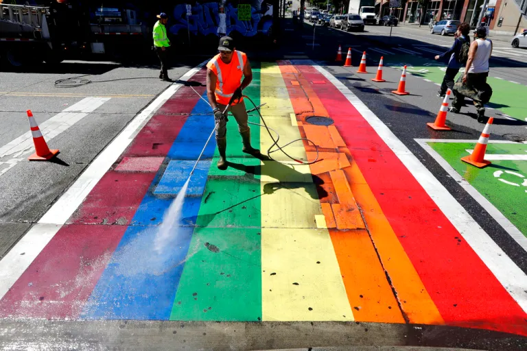 City worker Terrance Bryant pressure washes a rainbow-painted crosswalk in an annual clean-up ahead of Pride weekend on June 23, 2020, in Seattle. The usual LGBTQ+ Pride weekend of events was being replaced with virtual events starting June 26, with speakers, music and other online activities. (AP Photo/Elaine Thompson)