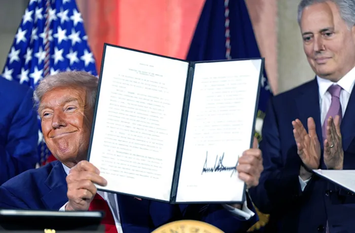 President Donald Trump holds a signed executive order with White House AI adviser David Sacks, right, at an AI summit.