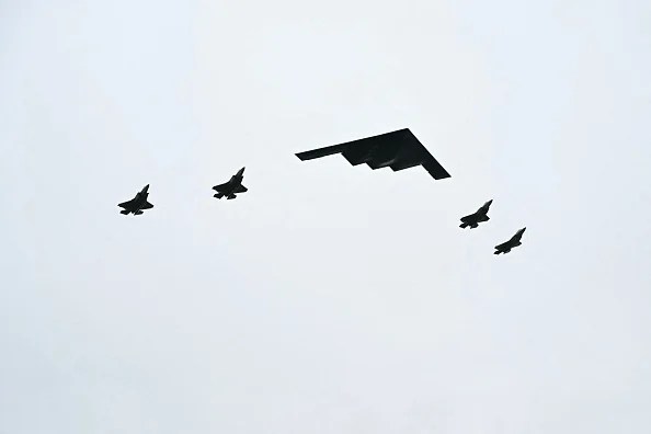 A B-2 bomber (C) and four F-35 fighter jets fly overhead as US President Donald Trump greets Russian President Vladimir Putin on the tarmac after they arrived at Joint Base Elmendorf-Richardson in Anchorage, Alaska, on August 15, 2025. Putin is in Alaska at the invitation of Trump in his first visit to a Western country since he ordered the 2022 invasion of Ukraine that has killed tens of thousands of people. 