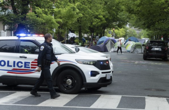 A Metropolitan D.C. Police officer closes the street near students protesting the Israel-Hamas war at the George Washington University in Washington, Saturday, April 27, 2024. (AP Photo/Cliff Owen)
