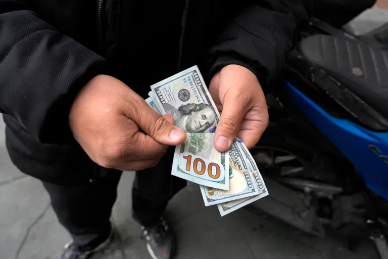 A street money exchanger poses for a photo without showing his face as he counts U.S. dollars at Ferdowsi square, Tehran's go-to venue for foreign currency exchange, in downtown Tehran, Iran, Wednesday, Feb. 5, 2025.