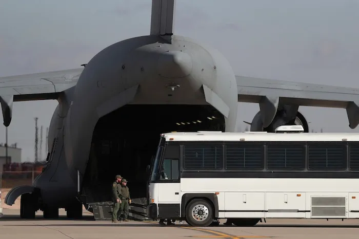 FILE - A military aircraft waits for migrants to board from a bus at Fort Bliss in El Paso, Tx., Thursday, Jan. 30, 2025, before deporting them to Guatemala. (AP Photo/Christian Chavez, File)