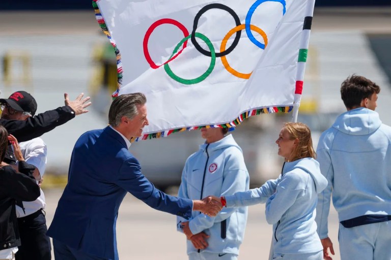 California Gov. Gavin Newsom (D), left, welcomes Team USA athletes arriving with the official Olympic flag returning to Los Angeles at Los Angeles International Airport on Monday, Aug. 12, 2024.