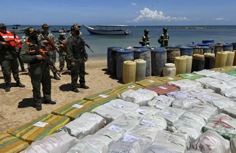 Sacks containing illegal drugs and plastic barrels containing fuel are displayed at a beachside campsite in the village of Tiraya, Venezuela.