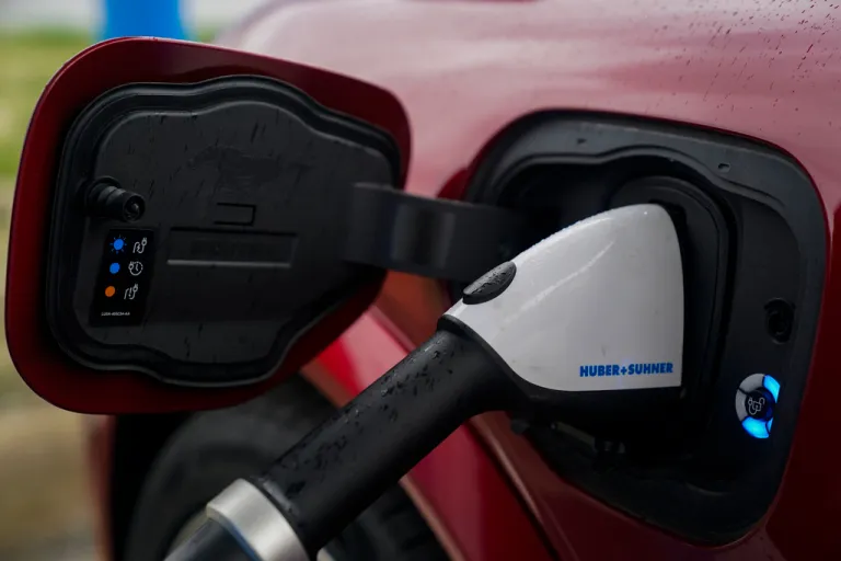 An electric vehicle charger is plugged into a red car.