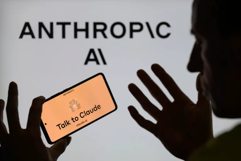 Talk to Claude is displayed on a smartphone with Anthropic Ai visible in the background.