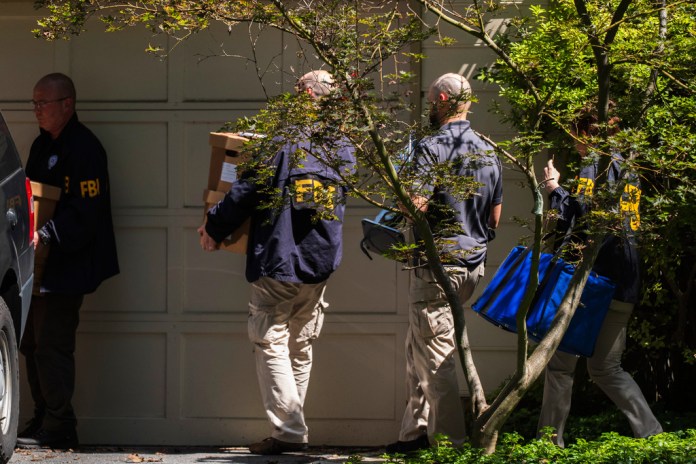 FBI agents carry bags and boxes out of former national security adviser John Bolton's house Friday, Aug. 22, 2025, in Bethesda, Md. (AP Photo/Manuel Balce Ceneta)