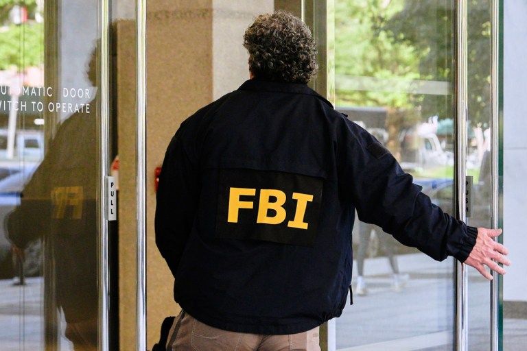 An FBI agent walks inside the front entrance of ex-Trump national security adviser John Bolton's Washington office.